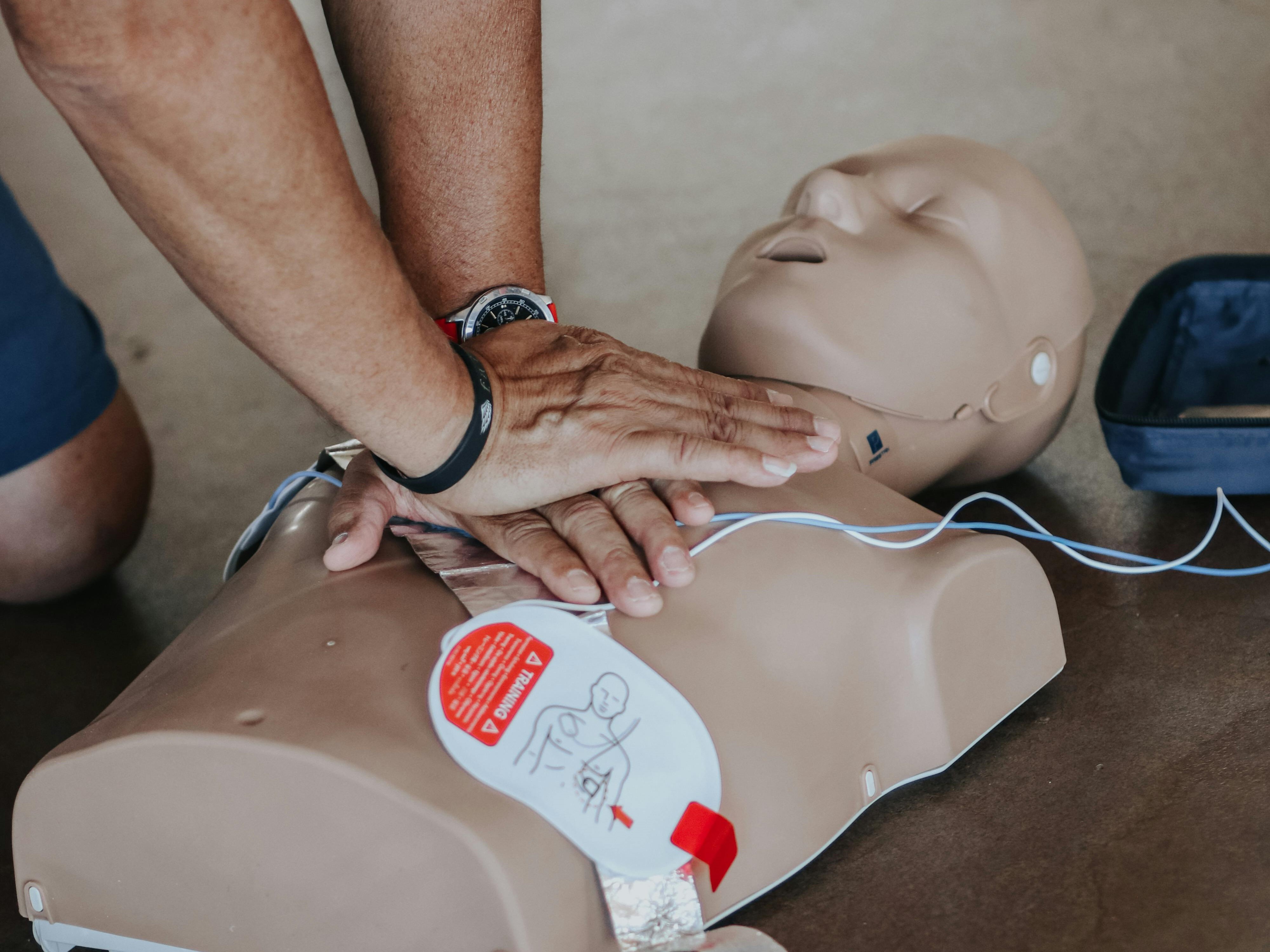 man doing CPR Compressions on mannekin